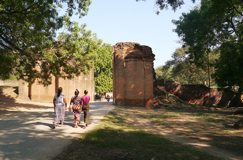 Old stone gate with modern Burmese women entering