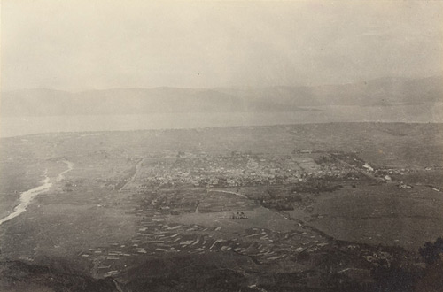 Distant view of walled town, river and mountains